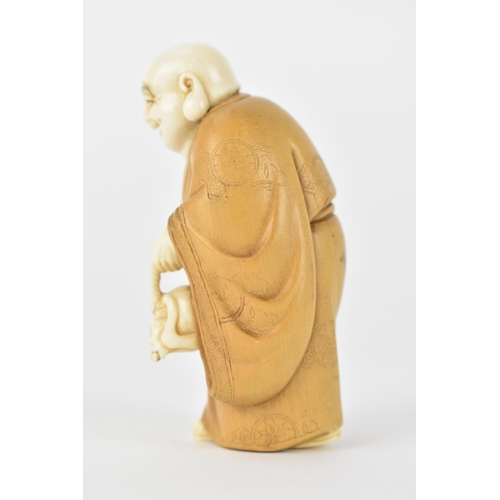 79 - An early 20th century Japanese wood and ivory Okimono of a Chinese man wearing a Kimono carrying a s... 