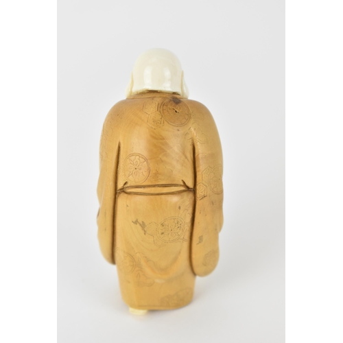 79 - An early 20th century Japanese wood and ivory Okimono of a Chinese man wearing a Kimono carrying a s... 