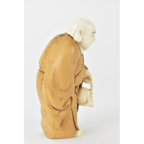 79 - An early 20th century Japanese wood and ivory Okimono of a Chinese man wearing a Kimono carrying a s... 