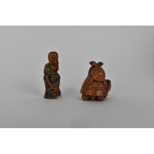 82 - A Quin dynasty and a later wooden netsuke of a deity wearing a robe and holding a fan with painted d... 