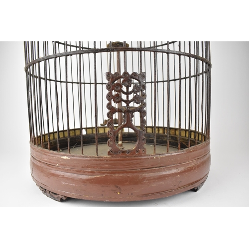 92 - A large 20th century Chinese brown painted wooden bird cage with a metal hook, a central perch and r... 