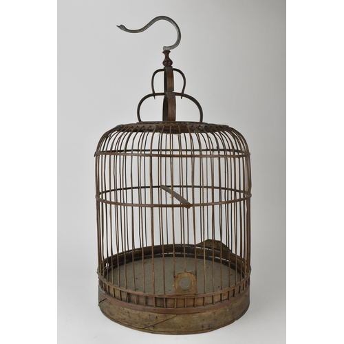 93 - A 20th century Chinese wooden and cane bird cage, with a metal swan neck hook and rising door on a p... 