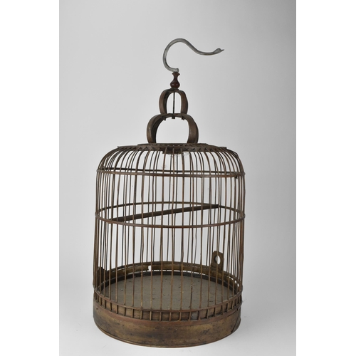 93 - A 20th century Chinese wooden and cane bird cage, with a metal swan neck hook and rising door on a p... 