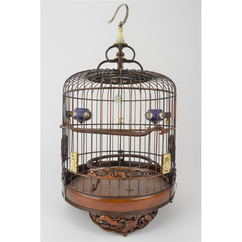 94 - A 20th century Chinese wooden and cane bird cage with a metal hook, a jade and bone finial, bone rin... 