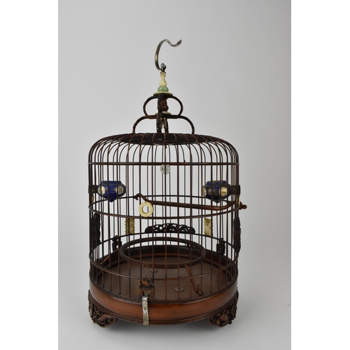 94 - A 20th century Chinese wooden and cane bird cage with a metal hook, a jade and bone finial, bone rin... 