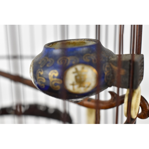 94 - A 20th century Chinese wooden and cane bird cage with a metal hook, a jade and bone finial, bone rin... 