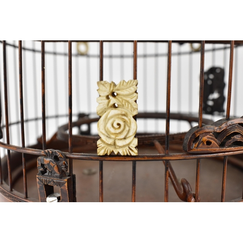 94 - A 20th century Chinese wooden and cane bird cage with a metal hook, a jade and bone finial, bone rin... 