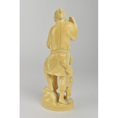 98 - A Japanese Meiji period ivory Okimono of a fisherman holding two fish and a net with a boy by his si... 