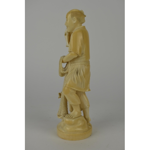 98 - A Japanese Meiji period ivory Okimono of a fisherman holding two fish and a net with a boy by his si... 