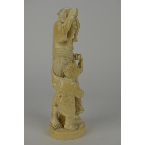 98 - A Japanese Meiji period ivory Okimono of a fisherman holding two fish and a net with a boy by his si... 