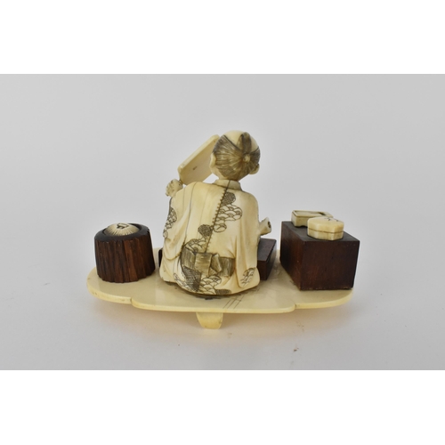 99 - A Japanese Meiji period ivory and wood Okimono of a craftsman holding a mirror with a book in front ... 