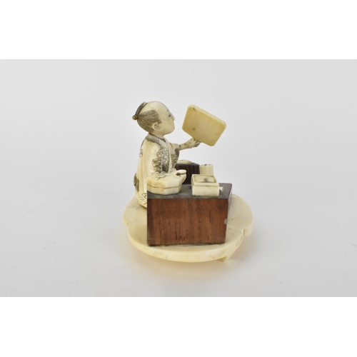 99 - A Japanese Meiji period ivory and wood Okimono of a craftsman holding a mirror with a book in front ... 