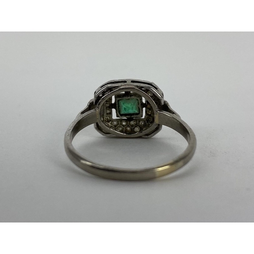 164 - An 18ct white gold and platinum ring set with a central emerald, 44mm x 3.5mm, with two bands of dia... 