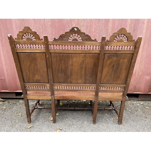 174 - An early 20th century French carved oak bench with a carved, pierced panelled back with country scen... 