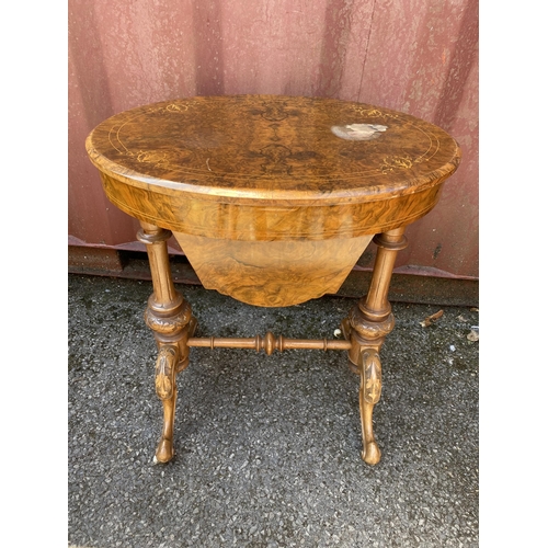 176 - A late Victorian figured walnut and marquetry oval work table, with a hinged lid, enclosing a compar... 