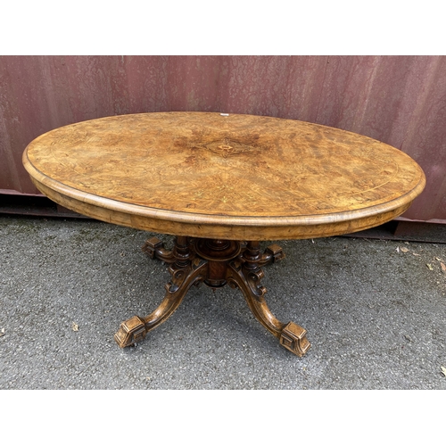 183 - A late Victorian figured walnut and marquetry loo table with an oval tip top, over four columns, on ... 