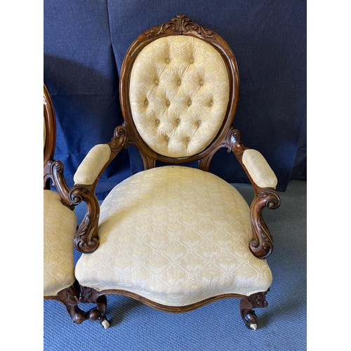 191 - A pair of mid Victorian walnut framed ladies and gentleman's chairs, each with carved crests, oval b... 