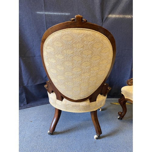 191 - A pair of mid Victorian walnut framed ladies and gentleman's chairs, each with carved crests, oval b... 