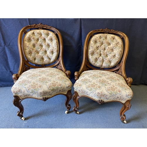 192 - A pair of late Victorian carved walnut framed chairs with oval button backs and serpentine front sea... 