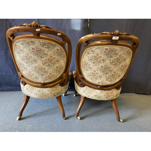 192 - A pair of late Victorian carved walnut framed chairs with oval button backs and serpentine front sea... 