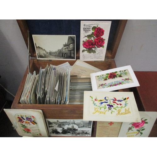 107 - A mixed lot to include early 20th century and later postcards housed in a wooden box to include embr... 