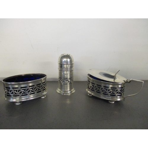 180 - An early 20th century silver three-piece cruet set with pierced decoration, blue glass liners and fl... 