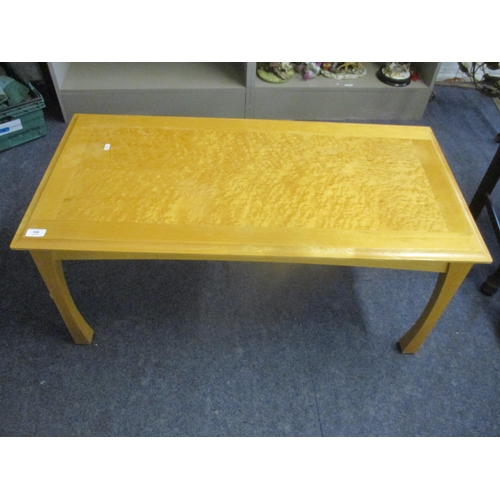 109 - A contemporary light wood coffee table with bird's eye maple veneered top, standing on four slightly... 