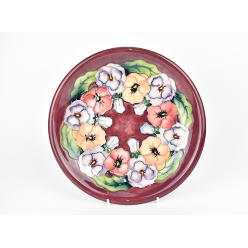 126 - A Moorcroft ceramic Pansy plate designed by Rachel Bishop, with impressed marks and signature to the... 