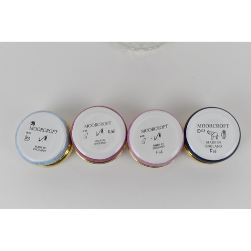 144 - A collection of Moorcroft Enamels Ltd pill boxes and a cut glass enamel lidded box, by various artis... 