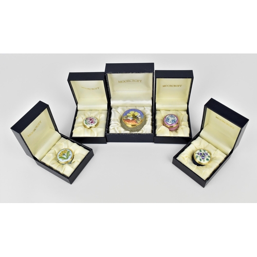 144 - A collection of Moorcroft Enamels Ltd pill boxes and a cut glass enamel lidded box, by various artis... 