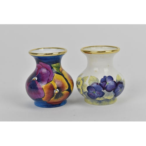 156 - Two Moorcroft Enamels Ltd miniature vases, both of baluster form with painted pansies, the blue grou... 