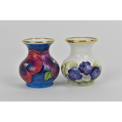 156 - Two Moorcroft Enamels Ltd miniature vases, both of baluster form with painted pansies, the blue grou... 