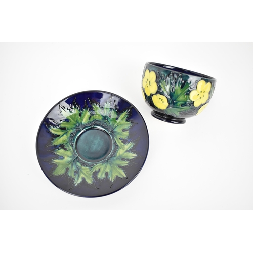 163 - A Moorcroft pottery 'Buttercup' pattern cup and saucer designed by Sally Tuffin, together with a mat... 