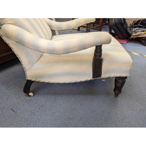 187 - A Victorian armchair upholstered in a striped fabric with a long seat, curved arms and ring turned l... 
