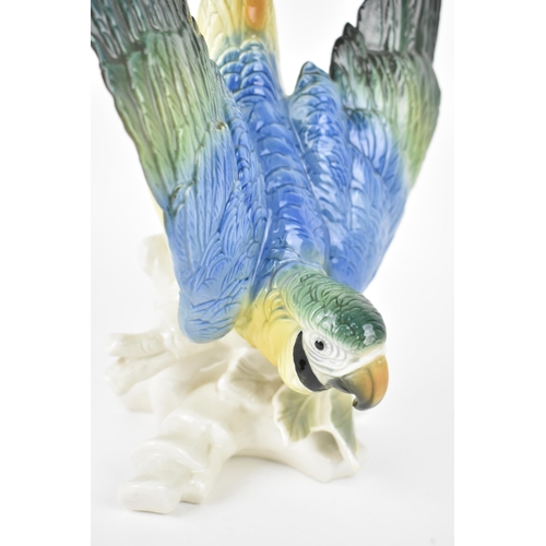 151 - A large Karl Ens (1802-1865) glazed porcelain macaw parrot, in a deep leaning position resting atop ... 