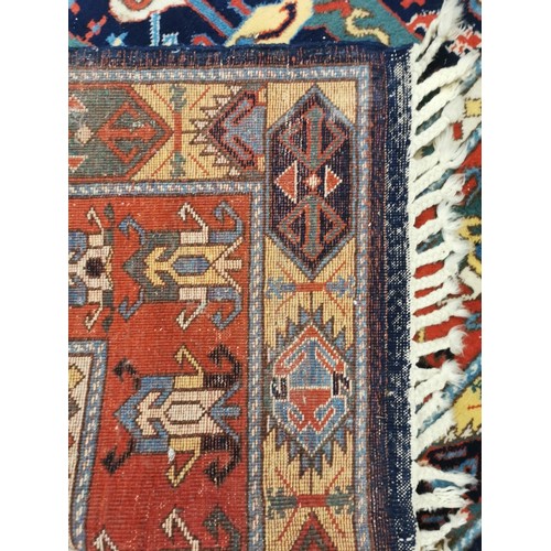 159 - A Turkish rug with repeated geometric motifs in pastel blue, red, yellow and green, 310cm x 210cm