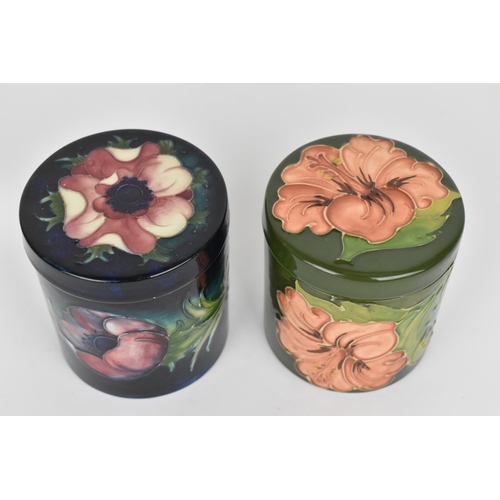 84 - Two Moorcroft pottery lidded pots, to include a 'Hibiscus' pattern one with coral flower on green gr... 