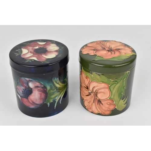 84 - Two Moorcroft pottery lidded pots, to include a 'Hibiscus' pattern one with coral flower on green gr... 