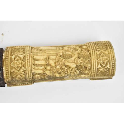 174 - A late 19th century oriental jambiya, the carved bone handle with figures between floral friezes wit... 