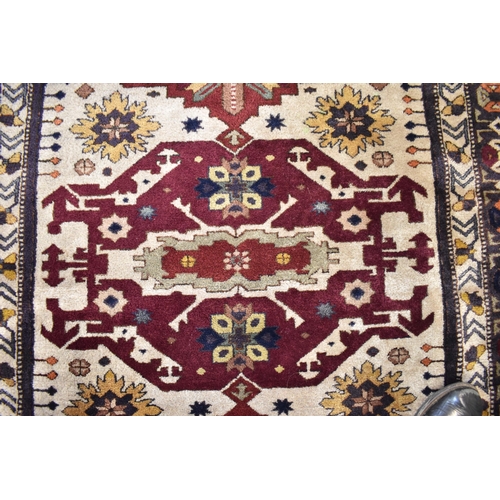 246 - A Kazak rug with three medallions on an off white ground in red, blue, yellow, orange and brown, 153... 