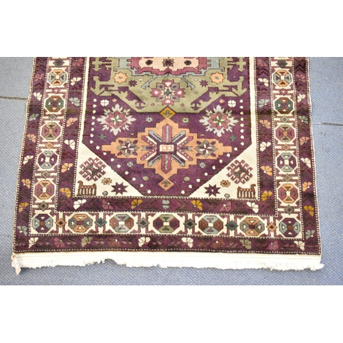 247 - A Kazak rug with three medallions on a purple ground, in green, blue and brown with off white spandr... 