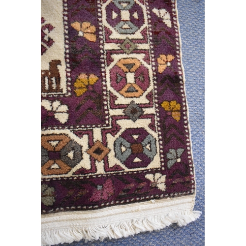 247 - A Kazak rug with three medallions on a purple ground, in green, blue and brown with off white spandr... 