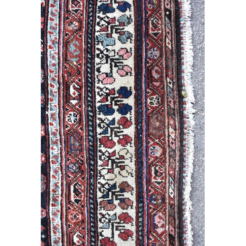 162 - A Bokhara rug with twin diamond medallions and repeated flowers on a dark blue ground, 171cm x 282cm