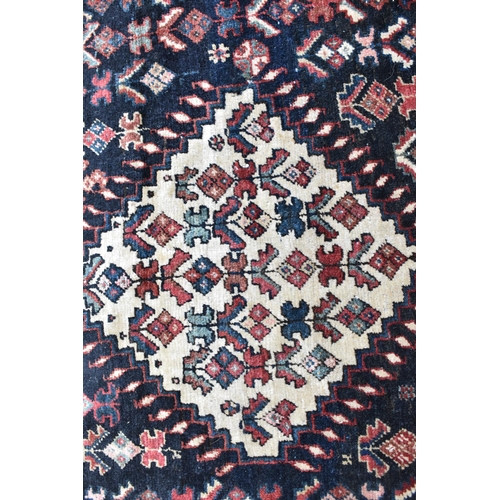 162 - A Bokhara rug with twin diamond medallions and repeated flowers on a dark blue ground, 171cm x 282cm