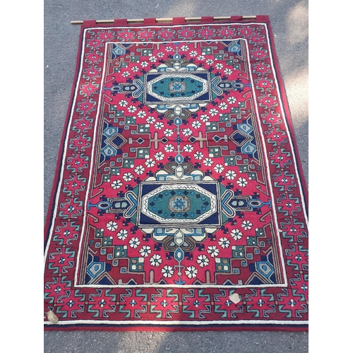 82 - A Debenhams crewel work wall tapestry with tab heading depicting crosses amongst the border in reds,... 