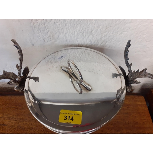 314 - A silver coloured ice bucket with side handles in the form of stags heads, 22cm high
Location: RAB