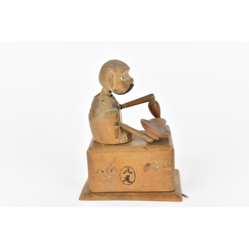 12 - A Japanese Meiji period wooden Kobe automaton toy, modelled as a figure holding a dish and a bottle,... 