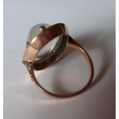 12 - A yellow metal ring, tests as 9ct gold, having a large moonstone on a raised mount, total weight 5.8... 