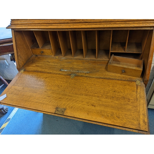 229 - An Arts & Crafts oak bureau bookcase having twin glazed doors above a fall flap and three drawers, 2... 