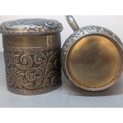 324 - A silver Christening mug and an Edwardian silver dressing table jar each with embossed decoration, 1... 